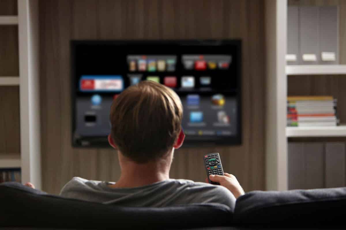 Person navigating streaming apps on a television, highlighting the impact of Connected TV Advertising in modern media consumption.